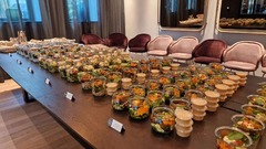 dean&david Catering | Stuttgart - Reihenweise frische Salate im Glas mit separatem Dressing, Wraps und Bowls auf einem langen Buffet für eine professionelle Veranstaltung.