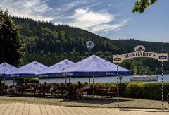 Der Biergarten des Maritim Hotels Titisee lädt mit gemütlichen Sitzplätzen im Freien und rustikalem Charme zum Entspannen ein. Gäste genießen erfrischende Getränke und Snacks in einer angenehmen Umgebung.