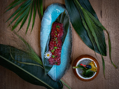Exotisch angerichtetes Longplate-Gericht mit Thunfischtatar, Edamame und Blüten, serviert auf blauen Keramiktellern mit Dip – tropisch inszeniert.