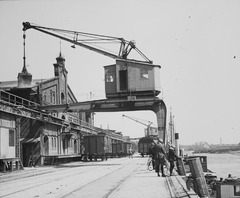 Eine historische Aufnahme des Oldenburger Hafens mit einem imposanten Hafenkran und Lagergebäuden. Dieses Bild zeigt die industrielle Vergangenheit der Stadt und die Verbindung zum wirtschaftlichen Zentrum.