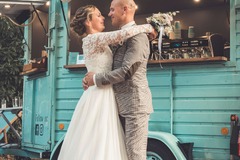 FirstLoveCoffee GmbH - Kaffee Catering Berlin - Hochzeitspaar vor türkisem Kaffeeanhänger mit Bio-Kaffee, Tee und frischen Waffeln, mobile Kaffeebar als Highlight für Hochzeitsfeiern.