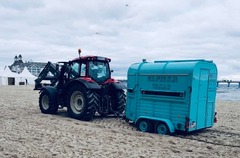 FirstLoveCoffee GmbH - Kaffee Catering Berlin - Türkiser Kaffeeanhänger am Strand wird von Traktor gezogen, mobile Kaffeebar für Outdoor-Events, Strandveranstaltungen und besondere Eventlocations.