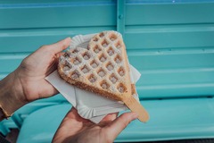 FirstLoveCoffee GmbH - Kaffee Catering Berlin - Frische Herzwaffel mit Puderzucker vor türkisem Anhänger, beliebtes Waffel Catering für Events, Hochzeiten, Firmenfeiern und mobile Kaffeebar.