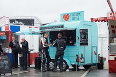 FirstLoveCoffee GmbH - Kaffee Catering Berlin - Türkiser Kaffeeanhänger auf Veranstaltungsgelände mit Gästen, Kaffeespezialitäten, frischen Waffeln und mobiler Barista-Bar für Events und Messen.