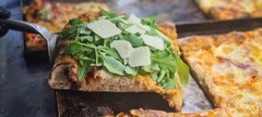 San Leone Mobile Pizza | Foodtruck & Catering Solingen - Frisch gebackene Pizza mit Rucola, gehobeltem Hartkäse und luftigem Pizzaboden. Italienische Pizza mit aromatischem Belag als Teil eines mobilen Pizza-Caterings für Veranstaltungen.
