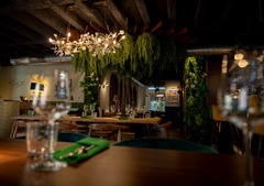 Stilvoll eingerichteter Restaurantbereich mit Holzbalkendecke, Kronleuchtern und üppiger Pflanzen-Dekoration – einladendes Ambiente mit moderner Eleganz.