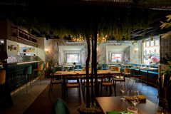 Heller und stilvoll eingerichteter Restaurantbereich mit großflächigen Sitzbereichen, Pflanzenakzenten und moderner Lichtgestaltung – ein Ort zum Wohlfühlen.