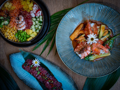 Dreiteilige Food-Komposition aus Poké Bowl, Lachsgericht und Longplate mit Thunfischtatar – kunstvoll angerichtet auf tropischem Hintergrund.