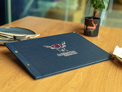 Speisekarte mit Logo des Restaurants Das Blümchen Friedrichshafen auf Holztisch – elegantes Design im Stil moderner Schwarzwald-Tapas.