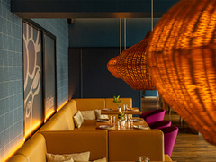 Gemütlicher Sitzbereich mit gelben Polsterbänken und Rattanlampen im Restaurant Das Blümchen Friedrichshafen – stilvolles Ambiente mit Schwarzwald-Charme.