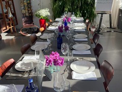 Geschlossene Gesellschaft bietet einen hell gedeckten Tisch mit weißen Tellern, Gläsern und Blumenschmuck für ein Social Dining Erlebnis in Hamburg.