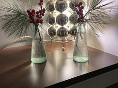 Geschlossene Gesellschaft präsentiert eine elegante Tischdekoration mit Glasvasen, roten Beerenzweigen und einem modernen Lichtobjekt für ein exklusives Ambiente in Hamburg.