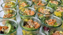 dean&david Catering | Pforzheim - Reihenweise Lachs Bowls im Glas mit Avocado, Mango, Salat, Sesam und cremigem Dressing als modernes Fingerfood für Veranstaltungen.