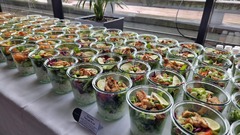 dean&david Catering | Pforzheim - Chicken Teriyaki Bowls im Glas mit Reis, Salat, Gurke, Limette und Frühlingszwiebeln auf einem hellen Buffet für Firmenveranstaltungen.