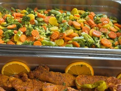 Die Feinschmecker Catering & Partyservice Hamburg - Professioneller Buffetaufbau mit verschiedenen warmen Speisen, darunter eine Auswahl an buntem, gedämpftem Gemüse wie Brokkoli und Karotten sowie feine Fleischgerichte.