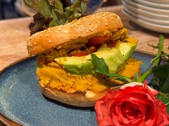 Die Feinschmecker Catering & Partyservice Hamburg - Frisch belegter Sesam-Bagel mit Avocado, Tomaten, herzhaftem Aufstrich und Blattsalat, serviert auf einem Teller. Vegetarische Speise für Café und Mittagessen.