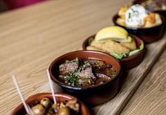 Auswahl kleiner Tapas-Schälchen auf dem Holztisch der Tapas Bar Léon. "Oma's Brett".